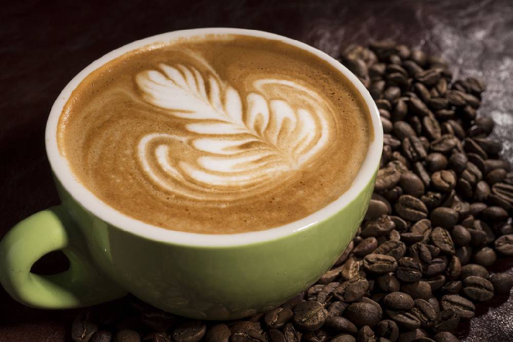 Pixxprint Cappucino zwischen Kaffeebohnen, Glasbild Rabatte dieses Monats